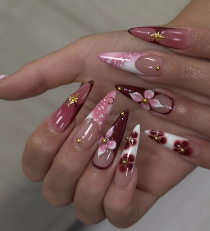 Burgundy stiletto nails with painted flowers and gold stars